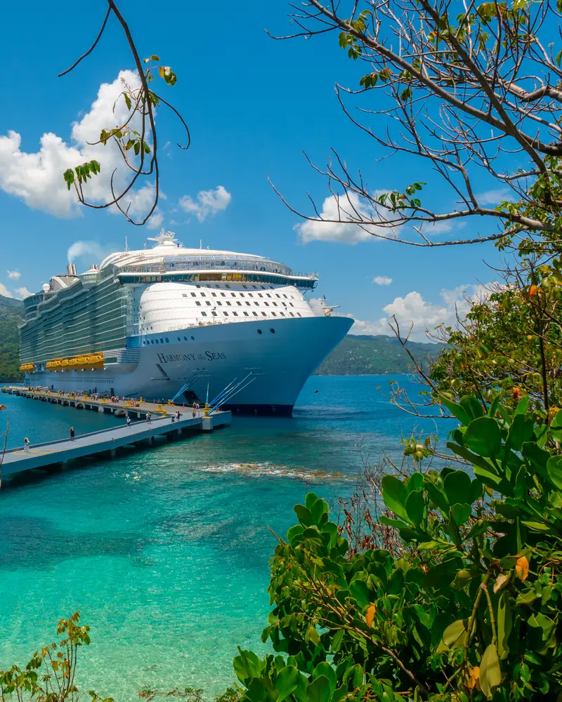 Cruise ship docked in a turquoise tropical bay surrounded by green hills