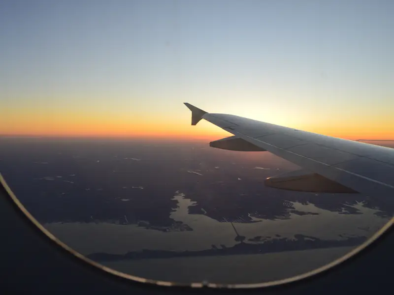 Airplane wing at sunset, seen through the cabin window
